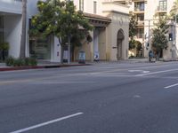 an empty street with several businesses on it and some cars going by the corner of the street