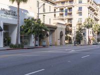 an empty street with several businesses on it and some cars going by the corner of the street