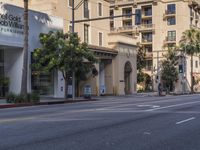 an empty street with several businesses on it and some cars going by the corner of the street