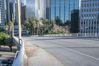 the street is empty in a big city with tall buildings behind it and a pedestrian walking across
