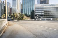 the street is empty in a big city with tall buildings behind it and a pedestrian walking across