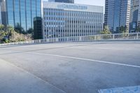 the street is empty in a big city with tall buildings behind it and a pedestrian walking across