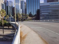 the street is empty in a big city with tall buildings behind it and a pedestrian walking across