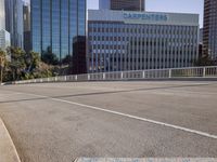 the street is empty in a big city with tall buildings behind it and a pedestrian walking across