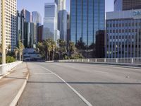 the street is empty in a big city with tall buildings behind it and a pedestrian walking across
