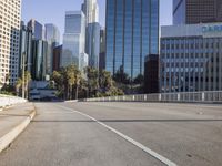 the street is empty in a big city with tall buildings behind it and a pedestrian walking across
