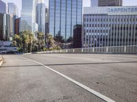 the street is empty in a big city with tall buildings behind it and a pedestrian walking across