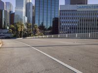 the street is empty in a big city with tall buildings behind it and a pedestrian walking across