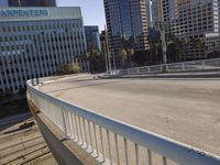 the street is empty in a big city with tall buildings behind it and a pedestrian walking across
