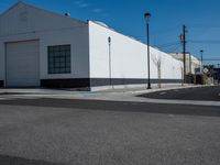 a empty street near a warehouse building and power lines in the background with blue skies