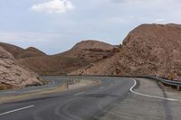 an empty street with a sign on it in the desert area near mountains and cliffs