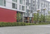 an empty street with cars parked next to a tall building on the opposite side of it