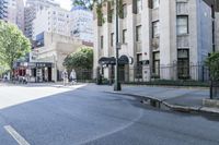 view down an empty street with people and buildings along the curb and on the sidewalk