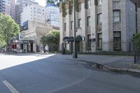 view down an empty street with people and buildings along the curb and on the sidewalk