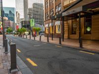 an empty street next to some buildings in a large city with red traffic lights and a person on the sidewalk