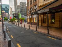 an empty street next to some buildings in a large city with red traffic lights and a person on the sidewalk