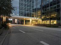 empty street in city area of large modern office building at dusk time lit from behind