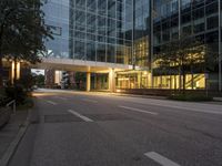 empty street in city area of large modern office building at dusk time lit from behind