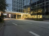 empty street in city area of large modern office building at dusk time lit from behind