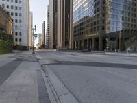 the empty street has an asphalt sidewalk with a hole in the middle, along with tall buildings