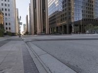 the empty street has an asphalt sidewalk with a hole in the middle, along with tall buildings