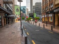 a view down an empty street lined with buildings and shopping shops in the background are tall buildings