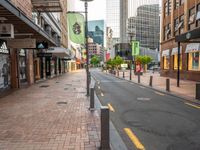 a view down an empty street lined with buildings and shopping shops in the background are tall buildings