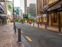 a view down an empty street lined with buildings and shopping shops in the background are tall buildings