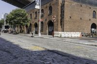 an empty street in front of an old building with two people walking underneath it and the walkway across it