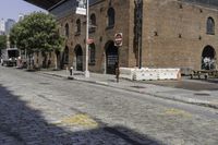 an empty street in front of an old building with two people walking underneath it and the walkway across it