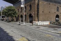 an empty street in front of an old building with two people walking underneath it and the walkway across it