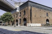 an empty street in front of an old building with two people walking underneath it and the walkway across it