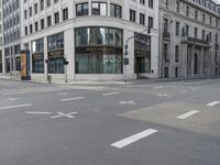 an empty street next to a tall building with many windows that have signs on each corner