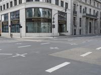 an empty street next to a tall building with many windows that have signs on each corner