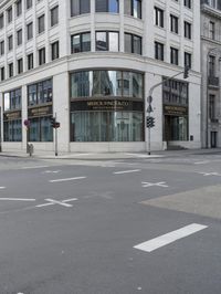 an empty street next to a tall building with many windows that have signs on each corner