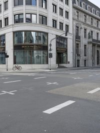 an empty street next to a tall building with many windows that have signs on each corner