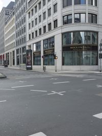 an empty street next to a tall building with many windows that have signs on each corner