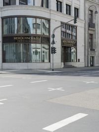 an empty street next to a tall building with many windows that have signs on each corner