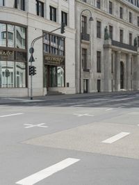 an empty street next to a tall building with many windows that have signs on each corner