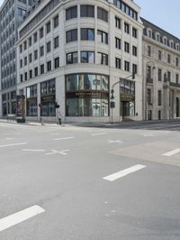 an empty street next to a tall building with many windows that have signs on each corner