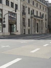 an empty street next to a tall building with many windows that have signs on each corner