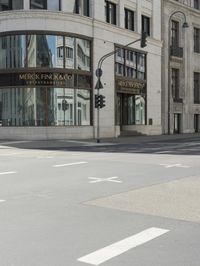 an empty street next to a tall building with many windows that have signs on each corner