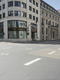 an empty street next to a tall building with many windows that have signs on each corner