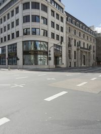 an empty street next to a tall building with many windows that have signs on each corner