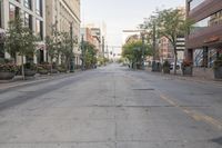 an empty, deserted street in front of buildings and cars on either side of it