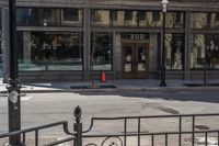 an empty street corner with traffic in the middle and glass windows that is closed on an old building