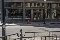 an empty street corner with traffic in the middle and glass windows that is closed on an old building