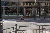 an empty street corner with traffic in the middle and glass windows that is closed on an old building