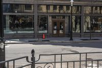 an empty street corner with traffic in the middle and glass windows that is closed on an old building