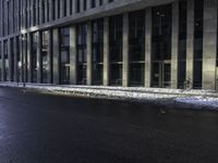 an empty street is covered by ice in front of the office building at night time